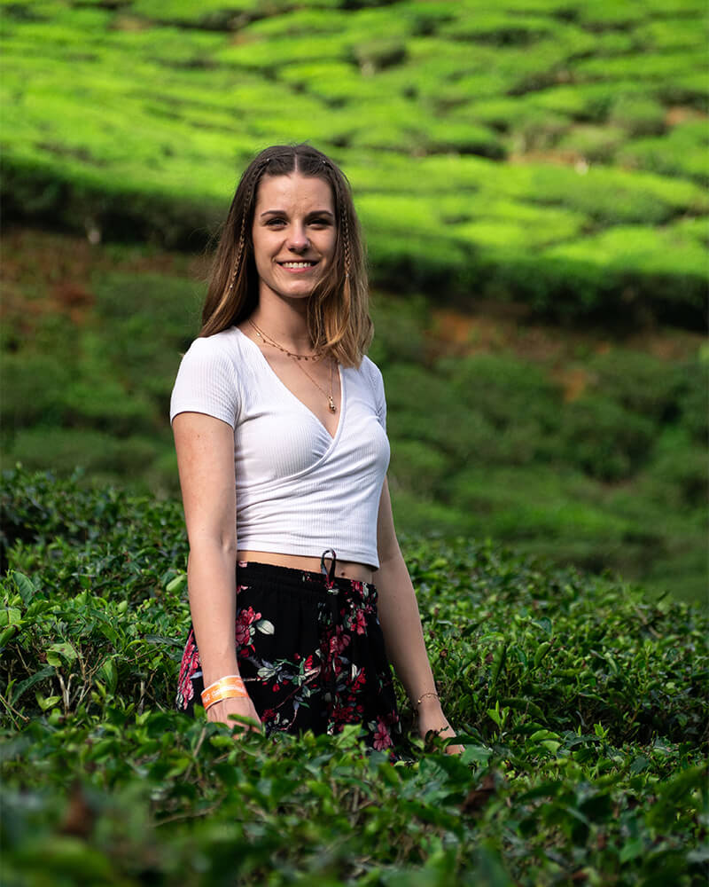 Junge Frau steht in Teeplantagen