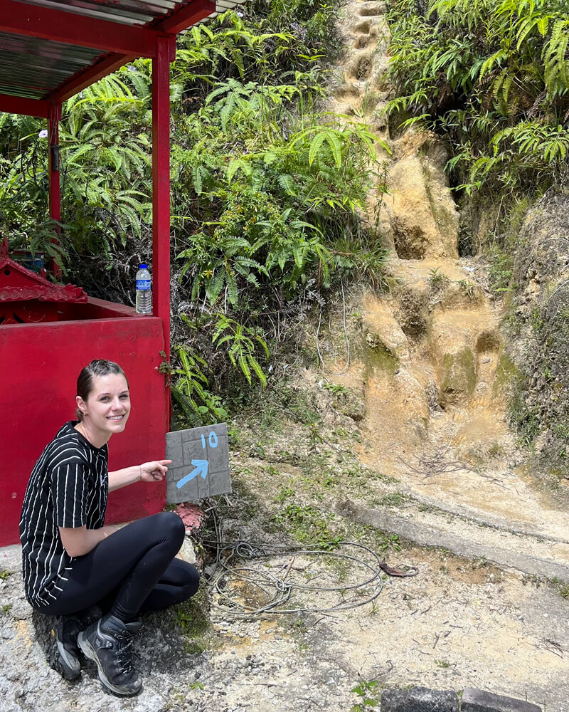 Junge Frau kniet vor Schild Trail Nr. 10