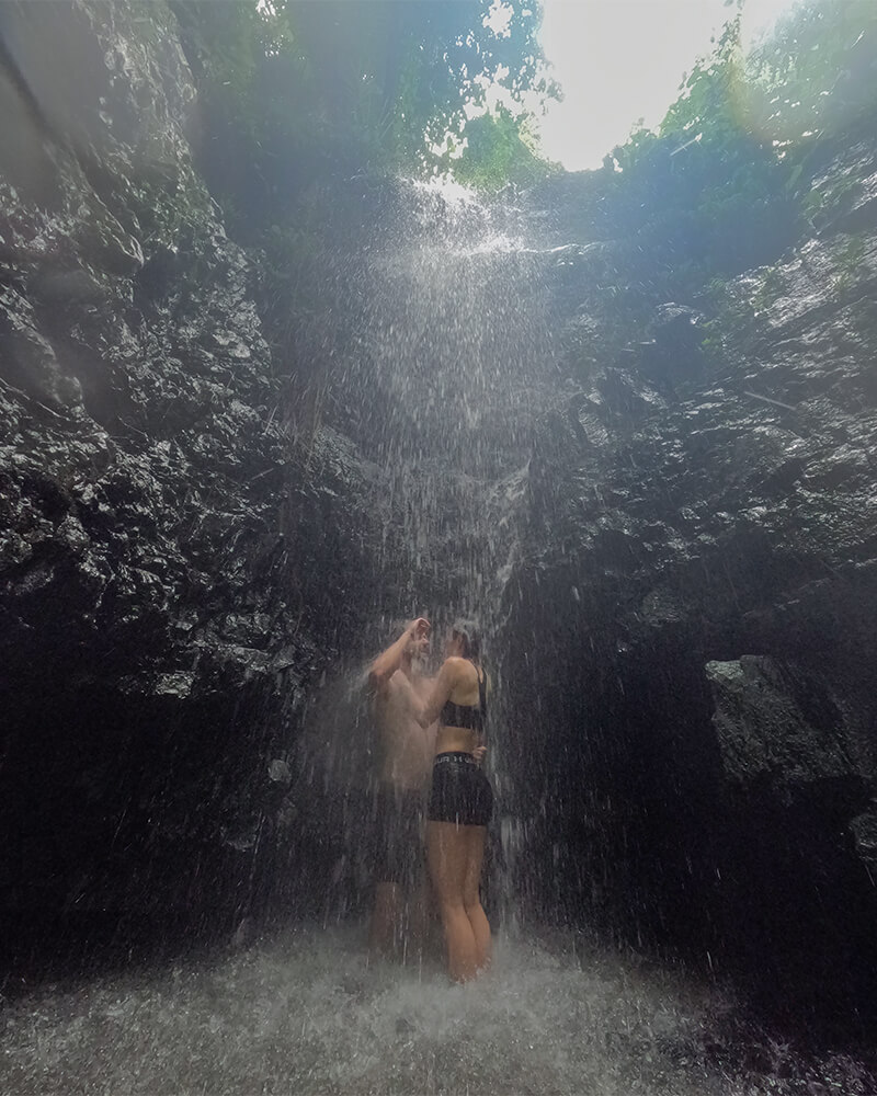 Junges Paar steht unter einem Wasserfall