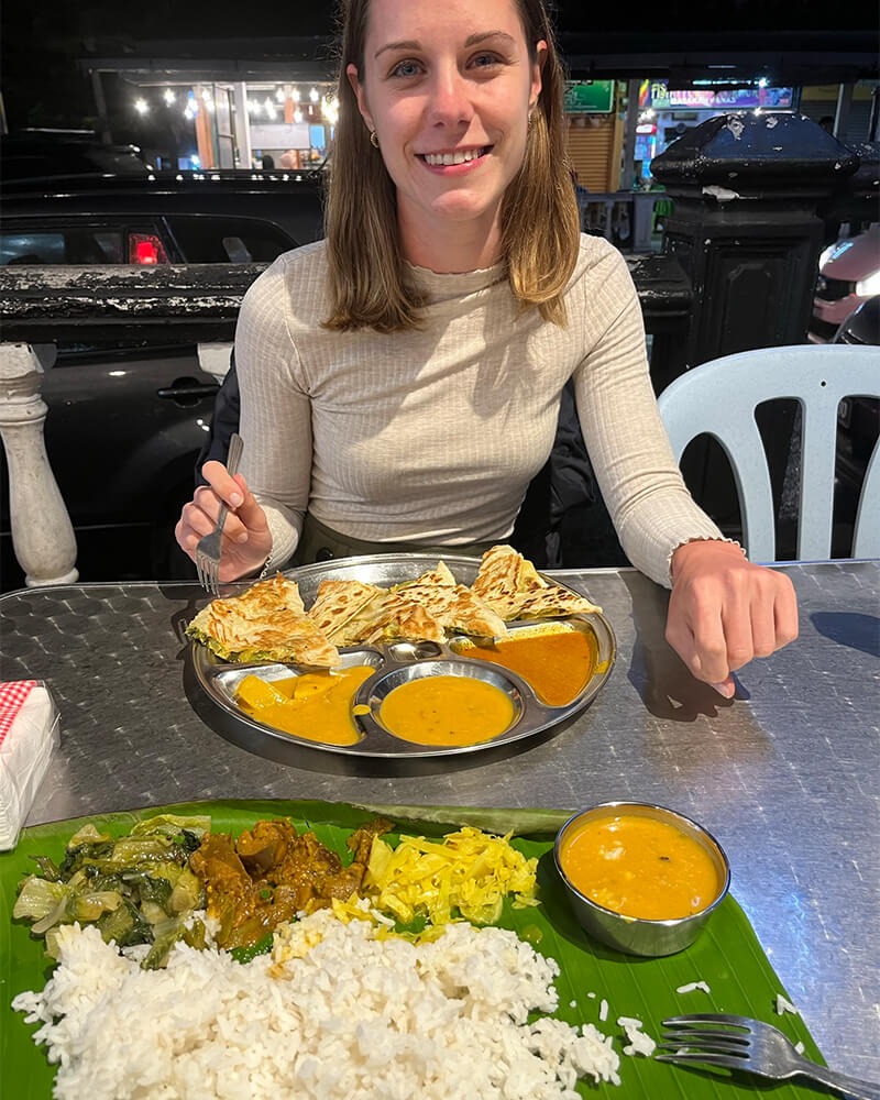 Junge Frau sitzt vor Indischem Essen