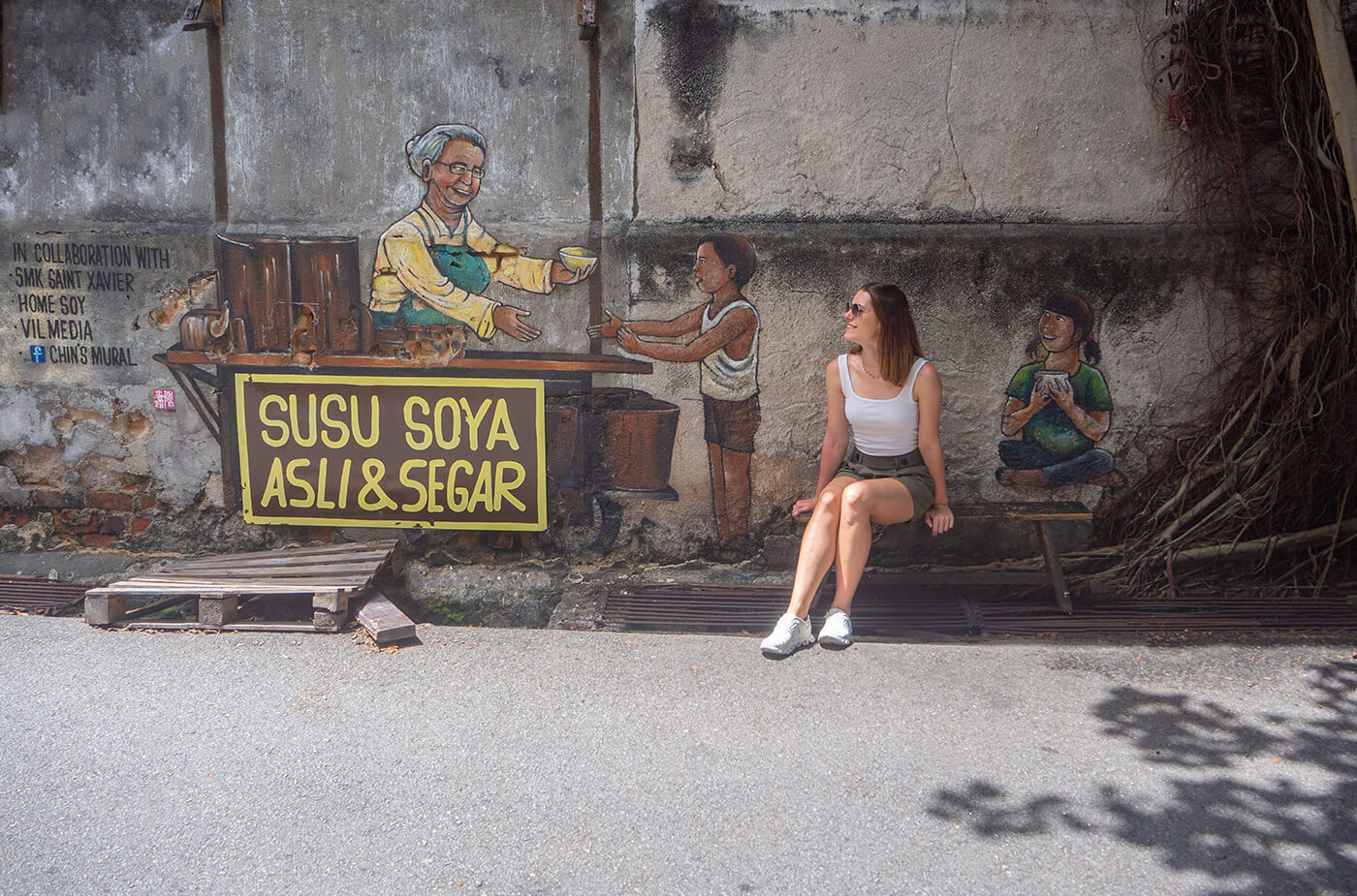 Frau sitzt vor Street Art in George Town