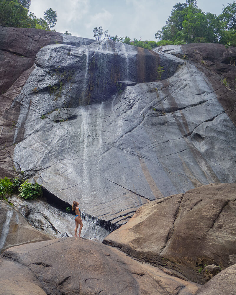 Frau in Bikini posiert vor einem Wasserfall