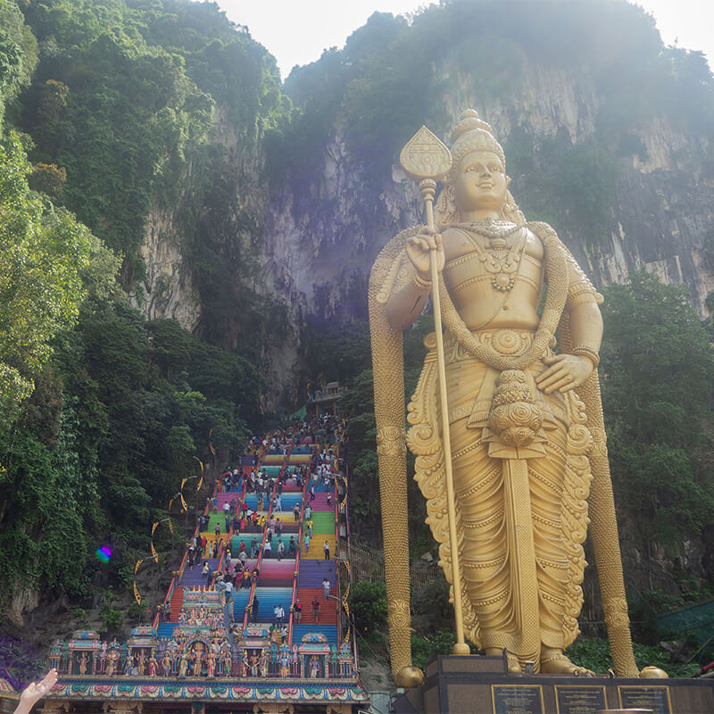 Eingang der Batu Caves mit bunten Treppen und großer goldener Statur