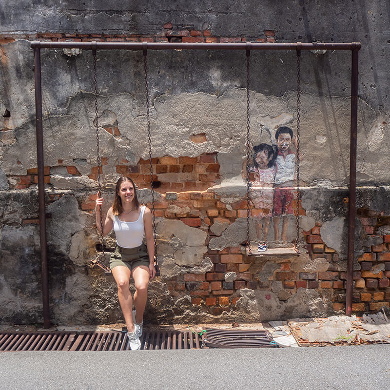 junge Frau an einem Streetart-Gemälde auf einer Schaukel