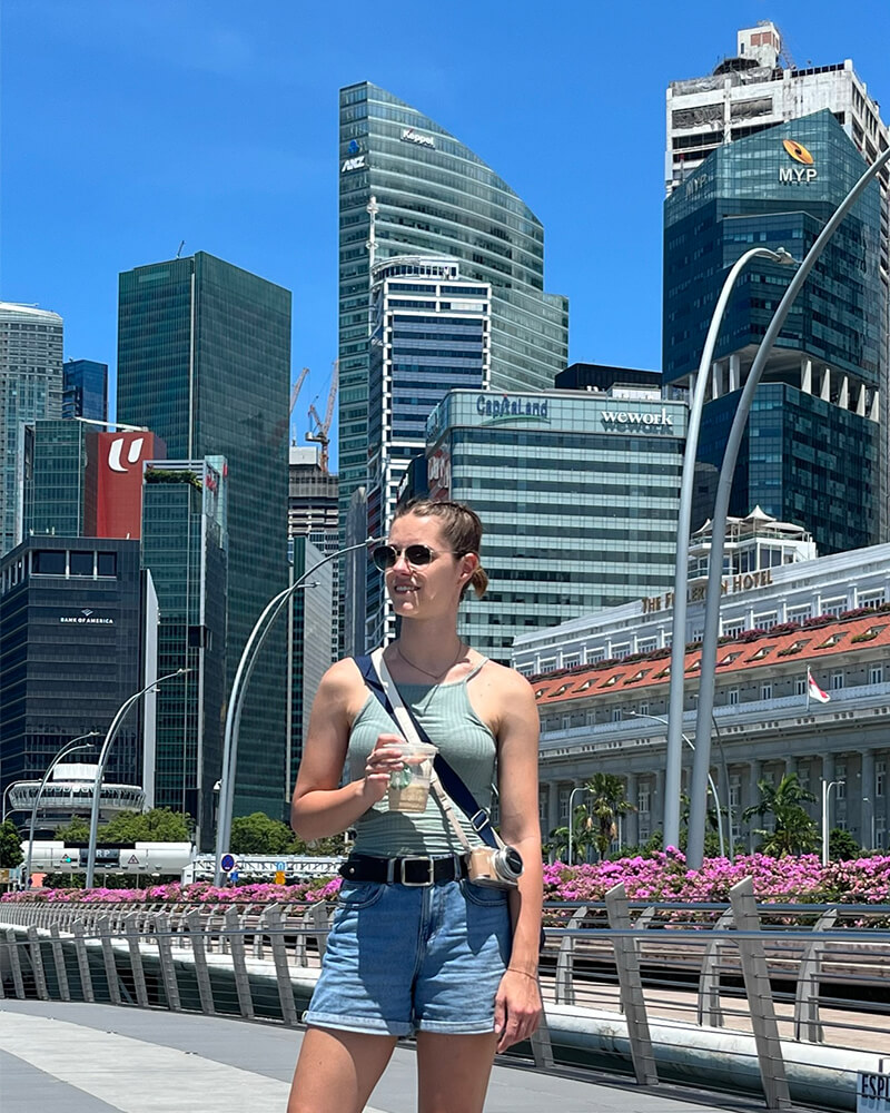junge Frau steht vor Singapurs Hochhäusern 