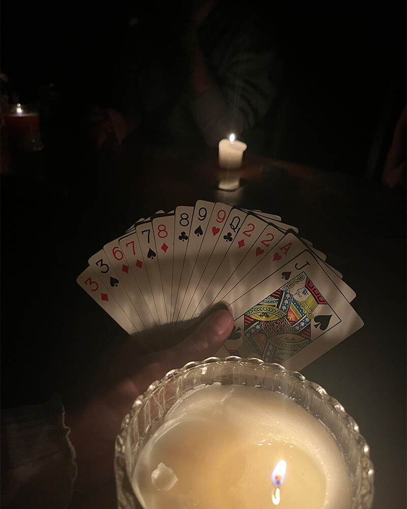 große Kerze und eine Hand, die einige Skart-Karten hält