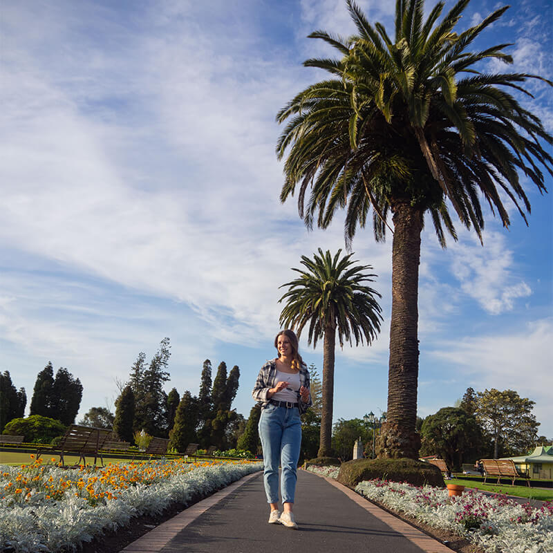 junge Frau läuft über eine Straße in einem Park mit Palmen