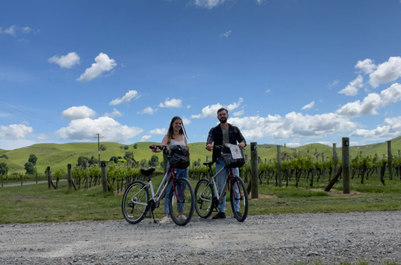 junges Paar mit Fahrrädern steht vor Weinbergen