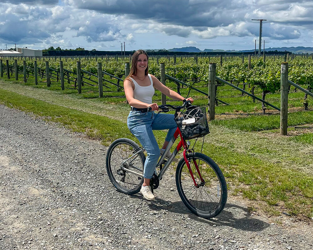 junge Frau fährt auf einem Fahrrad durch Weinberge