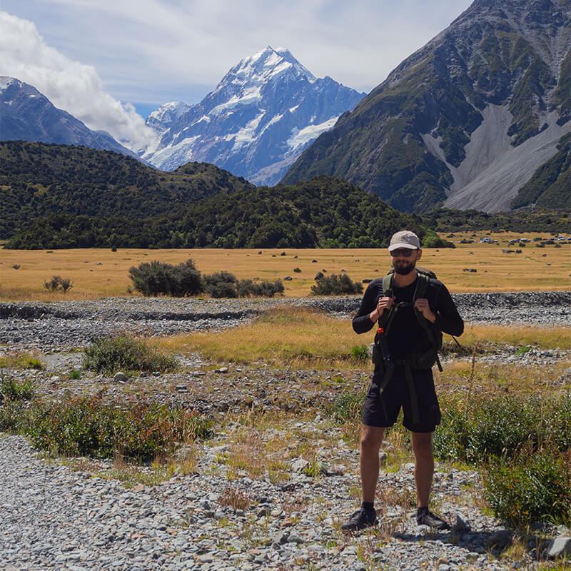 junger Mann im Wanderoutfit mit Mout Cook im Hintergrund