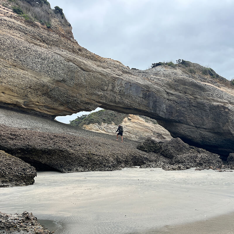 junger Mann klettert auf Felsen am Strand